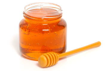 golden bee honey in a glass jar and honey dipper