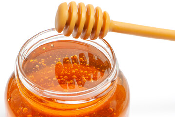 golden bee honey in a glass jar and honey dipper