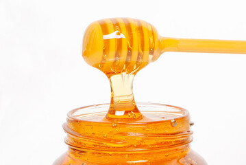 golden bee honey in a glass jar and honey dipper