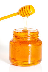 golden bee honey in a glass jar and honey dipper