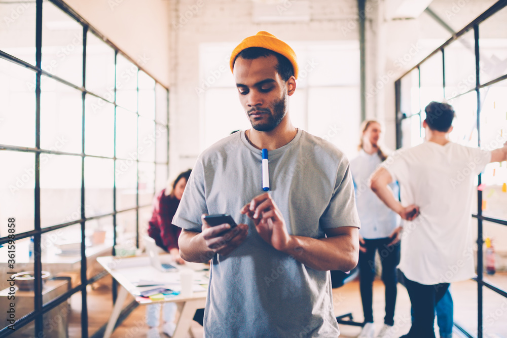 Poster thoughtful afro american team member reading income message on mobile during work break, dark-skinne