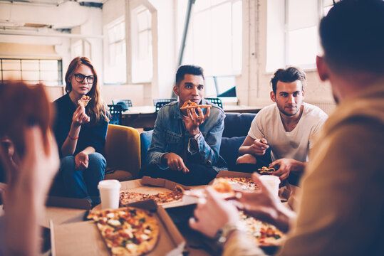 Multiracial Group Of International Student Talking To Each Other And Making Friends During Pizza Party, Hungry Male And Female Employees Having Lunch Break Together Eating In Coworking Space