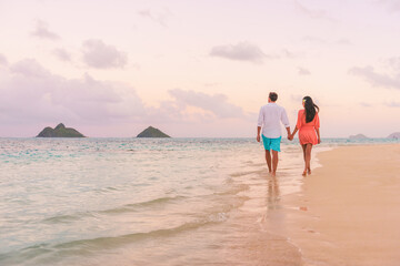 Beach vacation couple walking on romantic sunset night dusk sky beach walk relaxing on Hawaii...