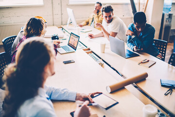 Male and female designers having informal meeting discussing working project in coworking office,...