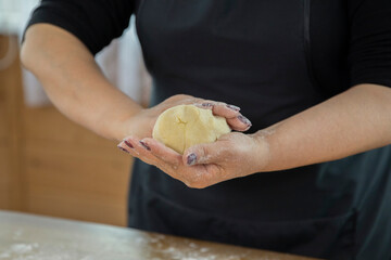 close up of housewife woman hands wrinkle dough in front of black apron for making homemade cookies in kitchen сookery class family traditions concept. Homemade baking lesson concept. blogging concept