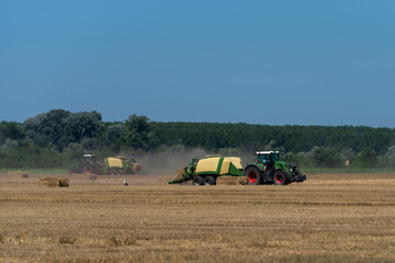 heavy machinery in the field performs agricultural work during the summer