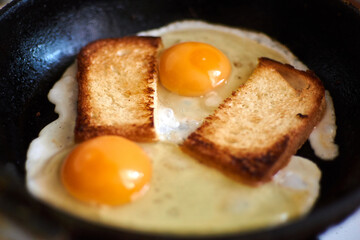 Two fried eggs with toast in a pan.