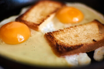 Two fried eggs with toast in a pan.