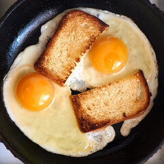 Two fried eggs with toast in a pan.
