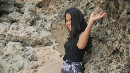 Indonesian girl posing on a beautiful and rocky beach in Bali. Idonezia.