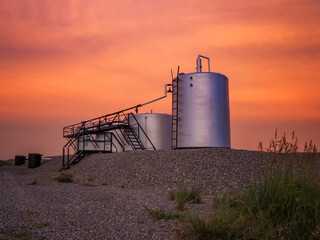 Oilwell at sunset with an orange and pink sky