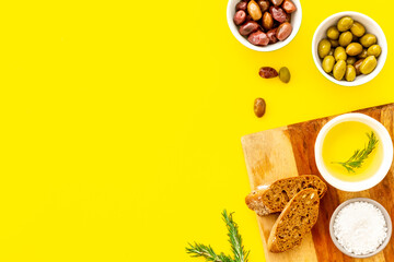 Appetizer. Olives in bowl and bread on cutting board from above space for text