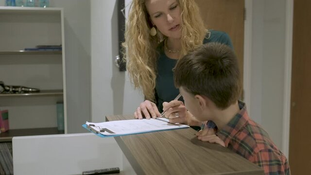 Mother and son filling out questionnaire at front desk