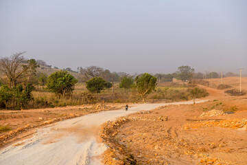 A loaded motorcycle goes down a dirt road.