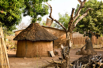 Traditional beninese house with firewood and a jump hanging from a tree.