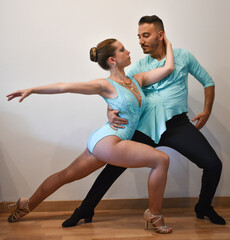 Professional Latino dance couple posing while dancing in light blue dresses