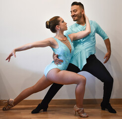 Professional Latino dance couple posing while dancing in light blue dresses