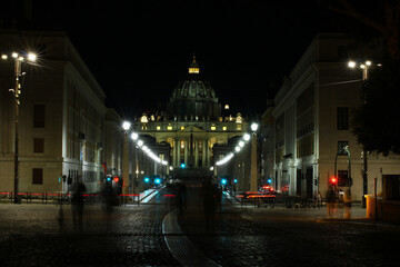 Rome, St. Peter's Basilica at night, traffic lights and street lamps, some tourists.