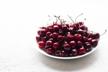 Cherry berry on a white plate . Summer berry. Berries on a plate on a white background. Article about berries.