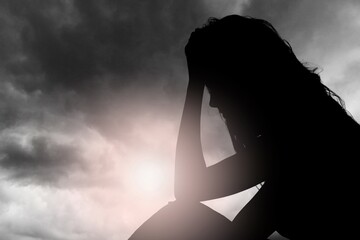 Silhouette of dark woman's head on gray sky background