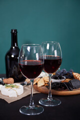 glasses of red wine and plate with assorted cheese, fruit and other snacks for party