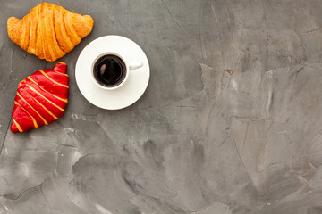 Croissants with coffee - breakfast on dark stone table top view