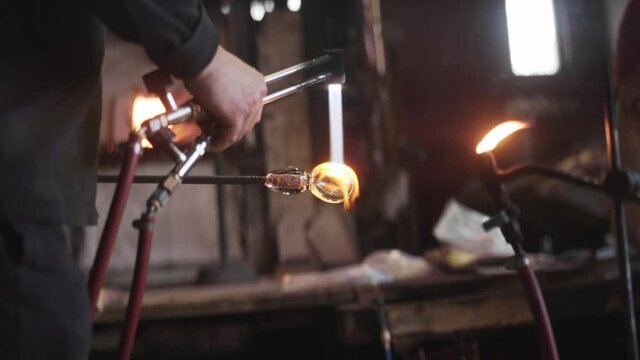 Master glass blowing artist heats fine crystal with blow torch - slow motion 