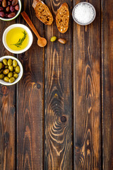 Obraz na płótnie Canvas Top view of olives, olive oil, bread on wooden table top view copy space