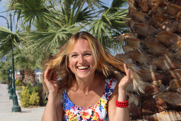 beautiful girl laughs beautifully on a background of palm trees.