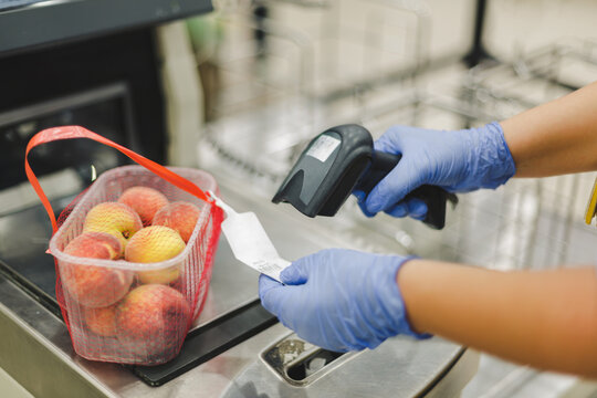 Scanning bar code. Woman or worker in blue medical gloves holding bar code scanner and scanning  paper on peach fruit. Shopping during the corona virus pandemic, selective focus