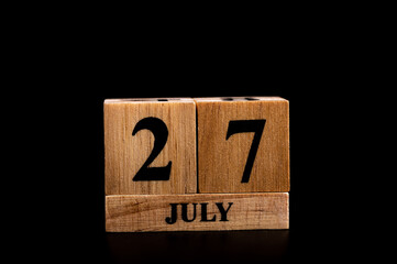 wooden calendar 27 July word on black background with copy space , selective focus at the calendar