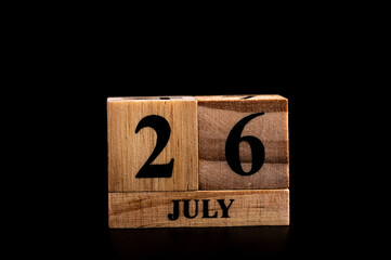 wooden calendar 26 July word on black background with copy space , selective focus at the calendar