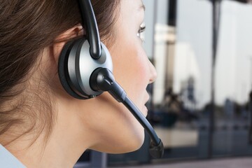 A young woman in headphones with a microphone working in a call center