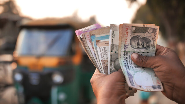 A Man Recounts Indian Rupee Money Amid Tuk Tuk.