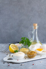 Ingredients for homemade mayonnaise sauce: mustard, eggs, olive oil, lemon, spices and herbs on...