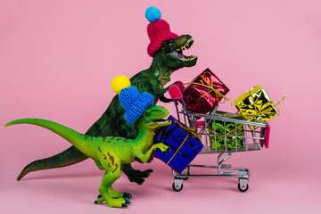 two cute dinosaurs in knitted hats with shopping trolley full of present boxes, sale concept