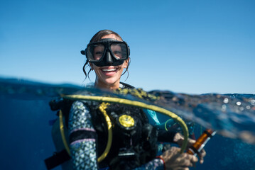 Woman SCUBA Diving Smiling in Ocean, young joyful woman with toothy smile swims at surface of blue...