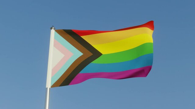 Inclusive LGBTQI+ Pride Flag with colours to include people of colour and the trans community. On a flag pole in the sun.