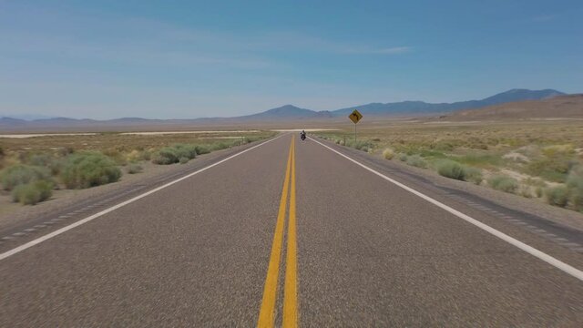 Americas most lonely highway filmed from the middle of the road as a big twin motorcycle start to ride on and vanishes in the distance