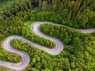 Aerial view of a green forest and an empty road traffic 