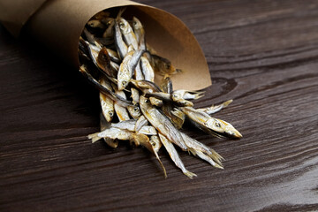 Sun-dried salty small fish. Stockfish on dark wooden background.
