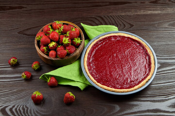 Strawberry pie in baking dish with fresh berries on wooden background