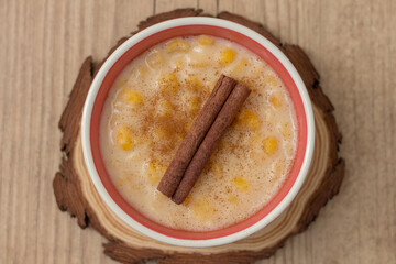 Hominy. Yellow corn with cinnamon in a ceramic bowl. Selective focus. Typical brazilian dessert of june festival in winter - Concept image.
