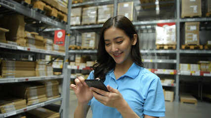 Business concepts. An Asian woman is checking products in a warehouse with an application from a mobile phone. 4k Resolution.