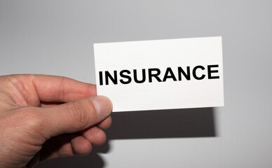 Message on the card INSURANCE, in hands of businessman.