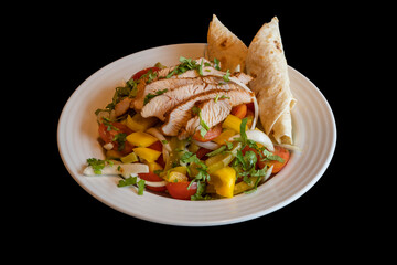 Grilled lean meat. The side dish is grilled vegetables with pita bread. Food on a white plate isolated on a black background.