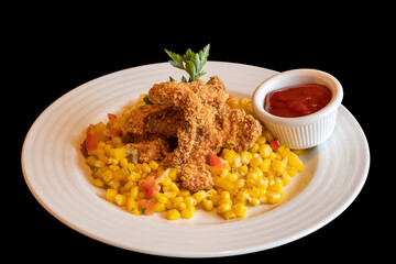 Breaded chicken wings with boiled corn and ketchup. Food on a white plate isolated on a black background.
