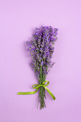 Top view lavender bouquet ribbon tied on purple background, portrait orientation