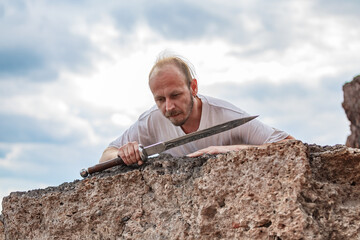 Warlike wanderer in the mountains resting after a battle with a dagger in his hand
