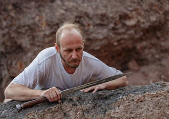 Warlike wanderer in the mountains resting after a battle with a dagger in his hand